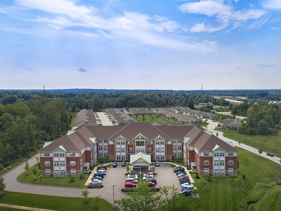 Aerial view of a large residential building with a parking lot in a suburban area.