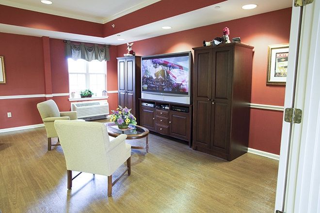 A cozy living room with a large television, elegant furniture, and warm decor.
