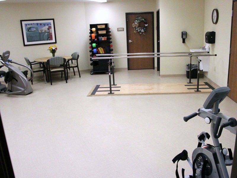 A physical therapy room equipped with exercise equipment and parallel bars.