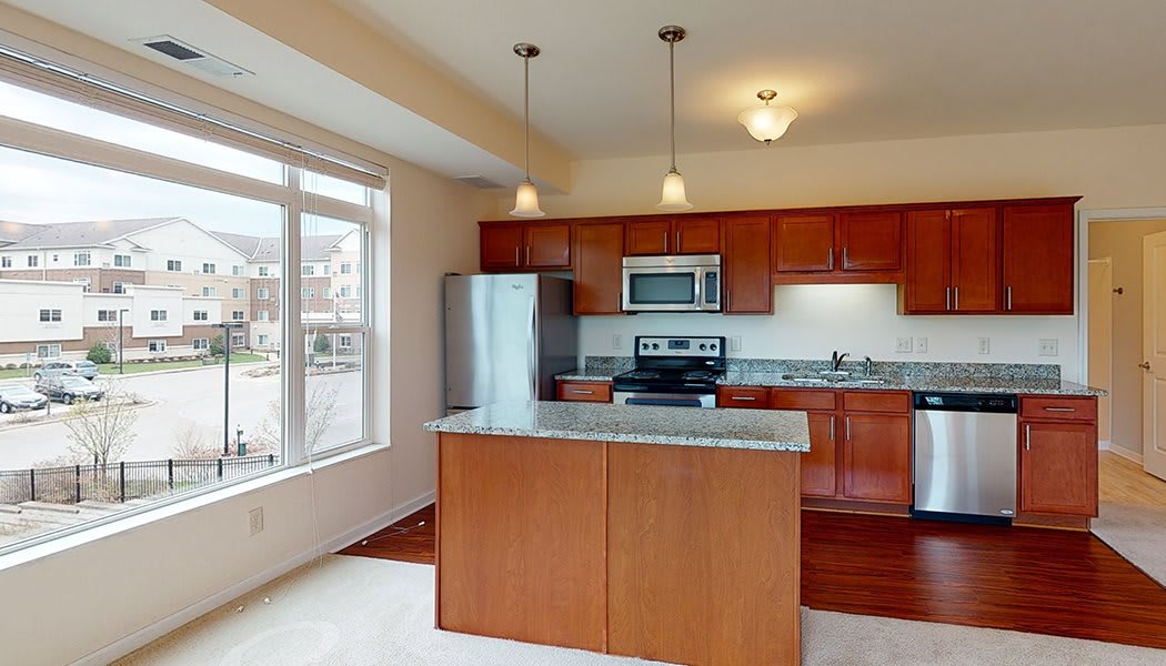 A modern kitchen with an island, featuring stainless steel appliances and granite countertops.