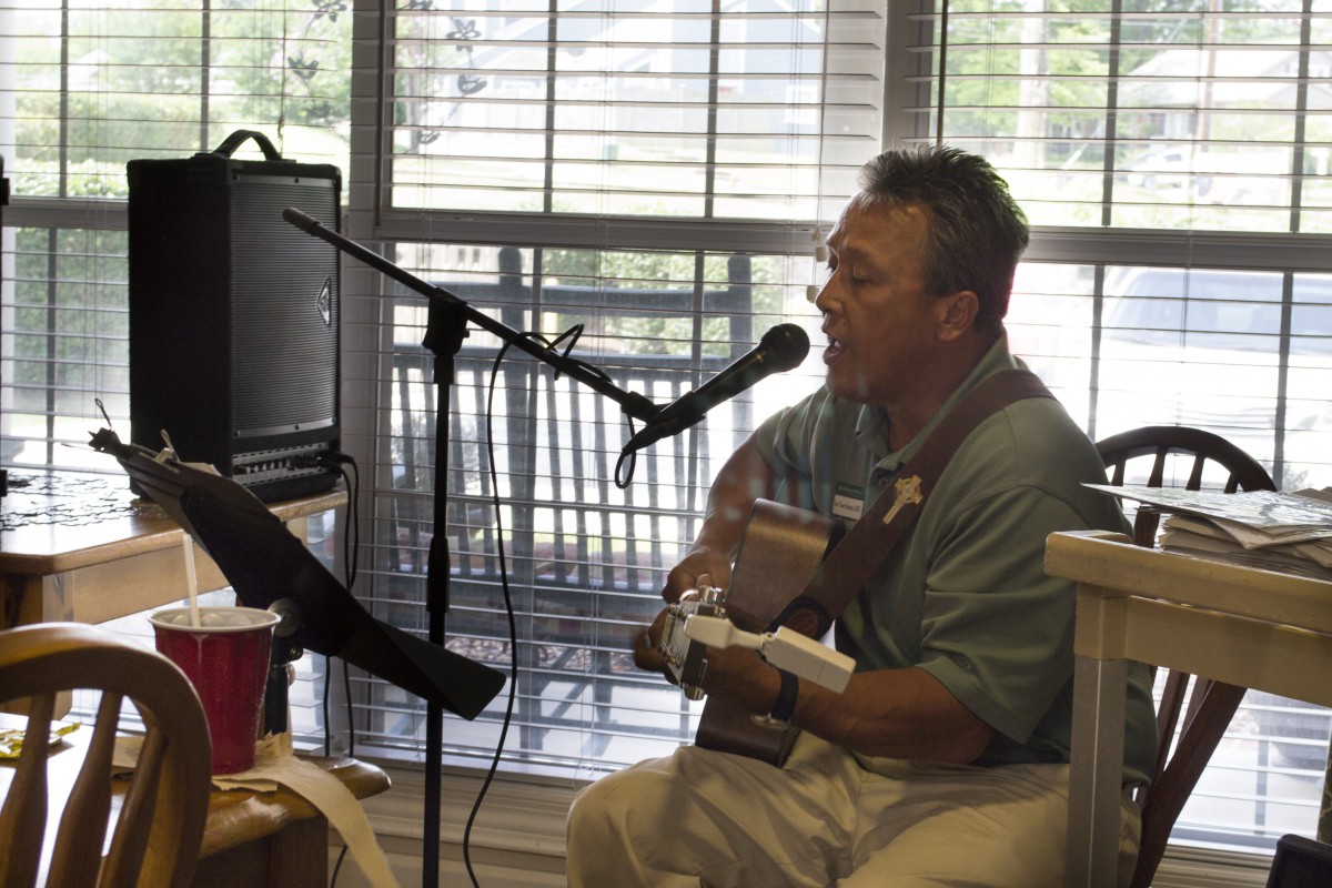 A musician performing indoors with a guitar and microphone.