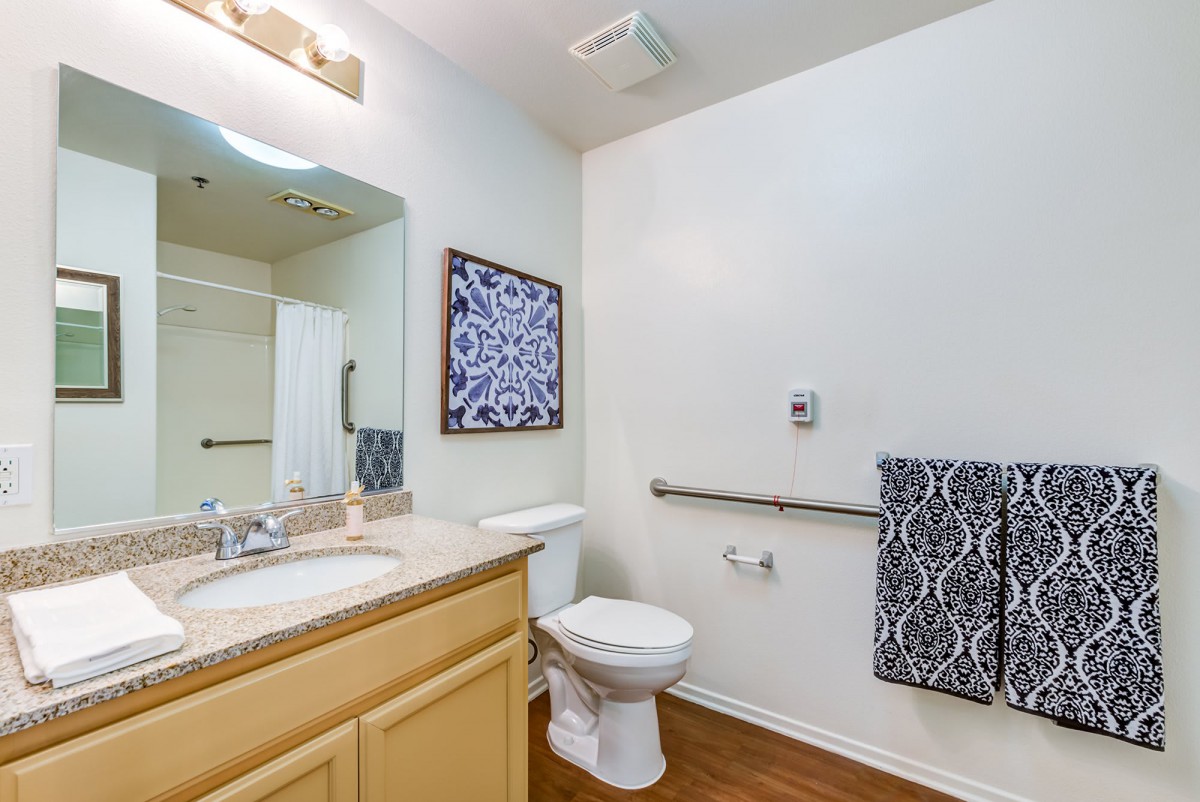 A clean and modern bathroom with a sink, toilet, and wall artwork.