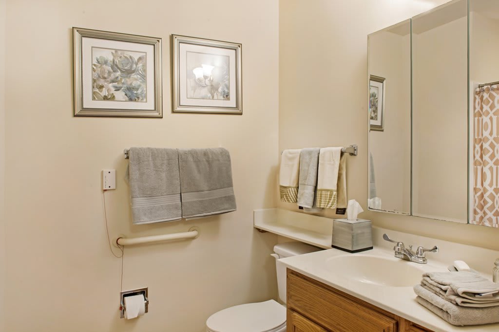 A neatly organized bathroom with towels, wall art, and a sink area.