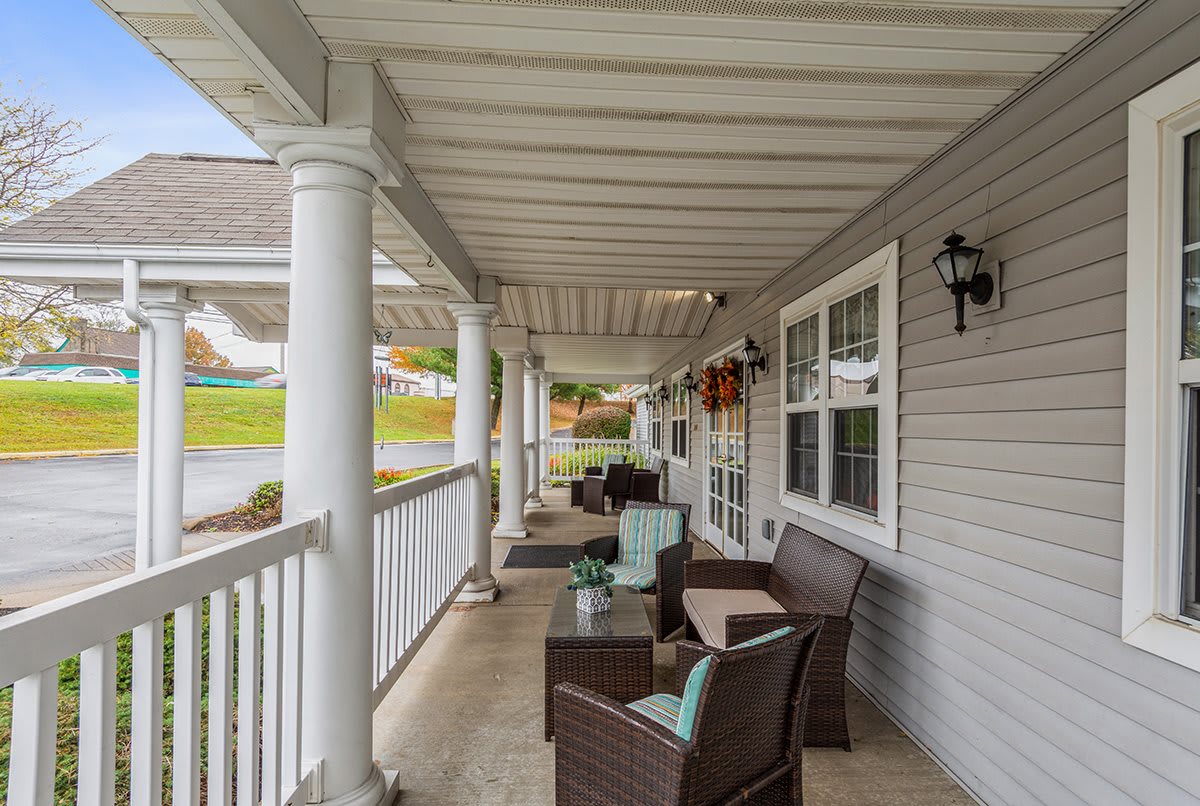 A cozy porch with outdoor seating and white columns, perfect for relaxing.