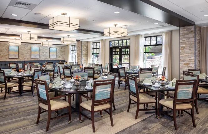 A modern and elegant dining room with neatly arranged tables and chairs under stylish lighting.