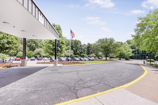 A view of the hotel entrance with an American flag and a landscaped parking area.