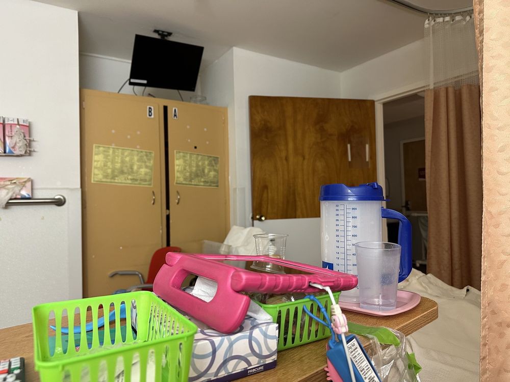 A hospital room with cabinets, TV, and medical supplies on a tray.