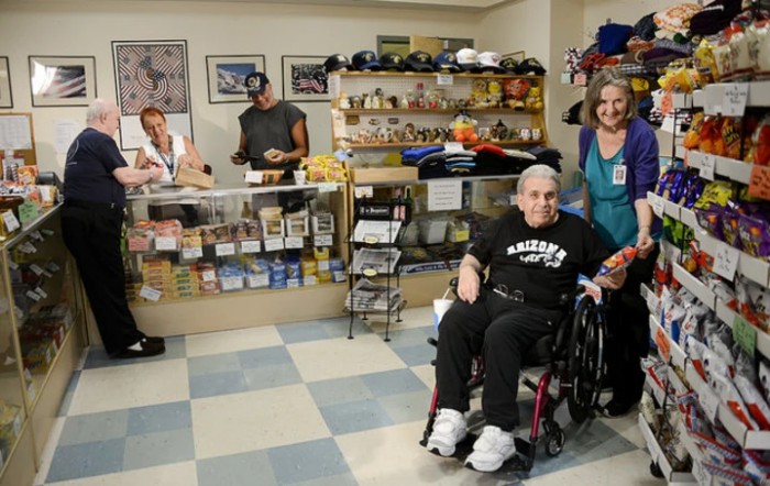 A group of people in a store, including an individual in a wheelchair, near a counter with display shelves.