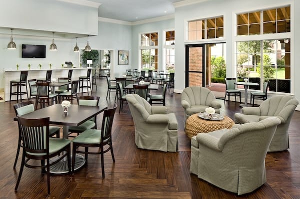 A spacious and well-lit lounge area with various seating arrangements, including tables and cushioned chairs.