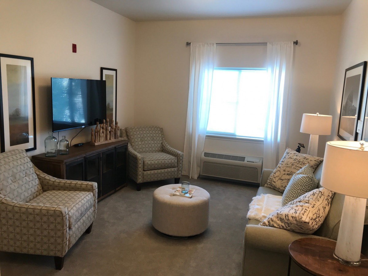 A cozy living room with a television, sofa, chairs, and a coffee table.