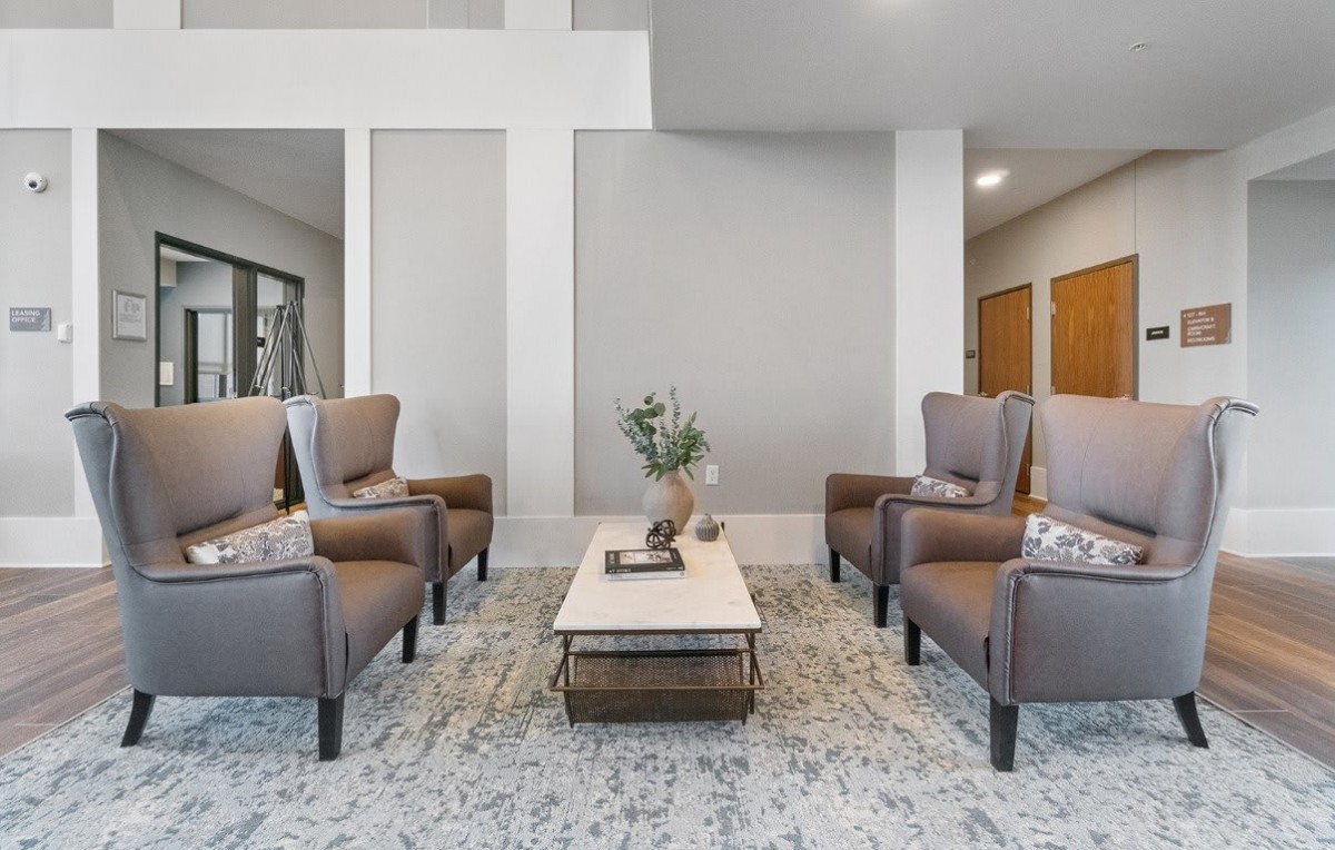 A modern lobby with comfortable chairs and a coffee table, featuring elegant decor.