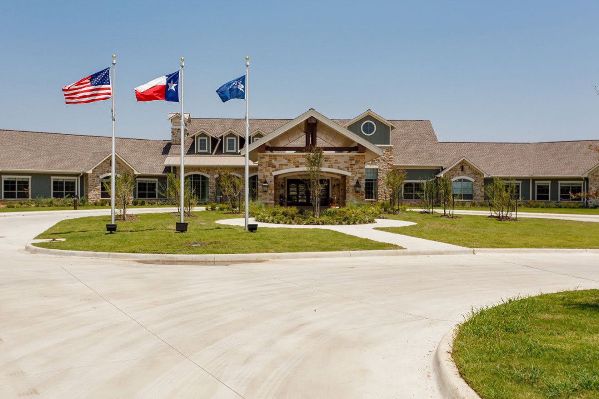 A large building with multiple flags in front, surrounded by a well-maintained landscape and driveway.