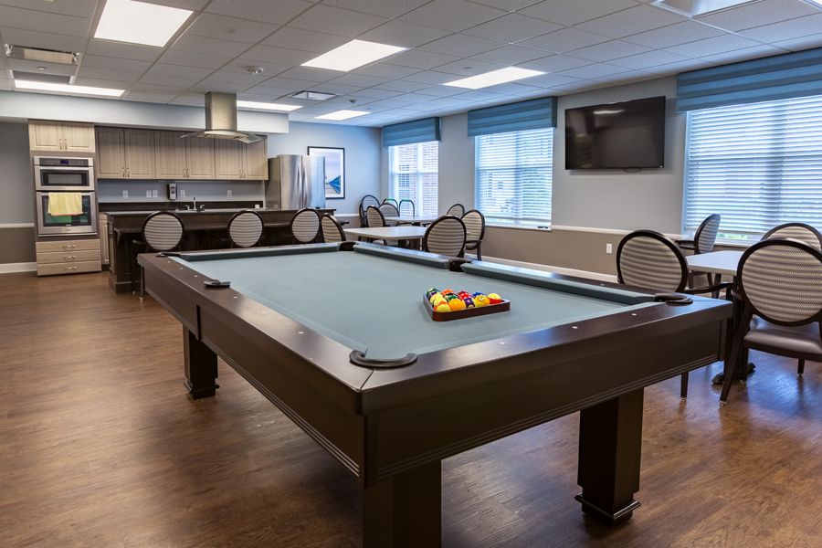 A modern game room featuring a pool table with billiard balls arranged, set in a well-lit and comfortable environment.