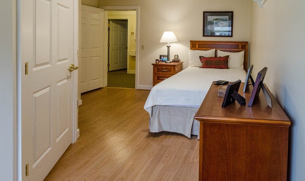 A cozy bedroom with a neatly made bed, wooden furniture, and warm lighting.