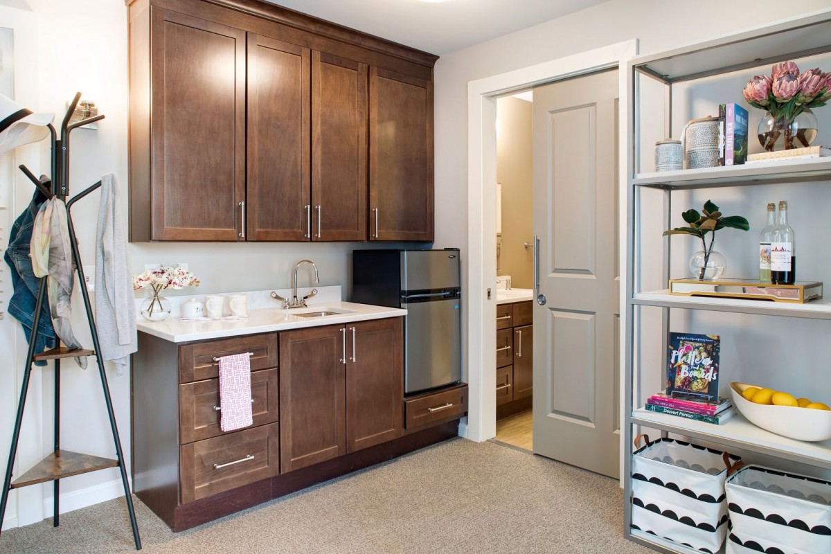 A modern kitchen area featuring wooden cabinetry, a sink, and shelving.