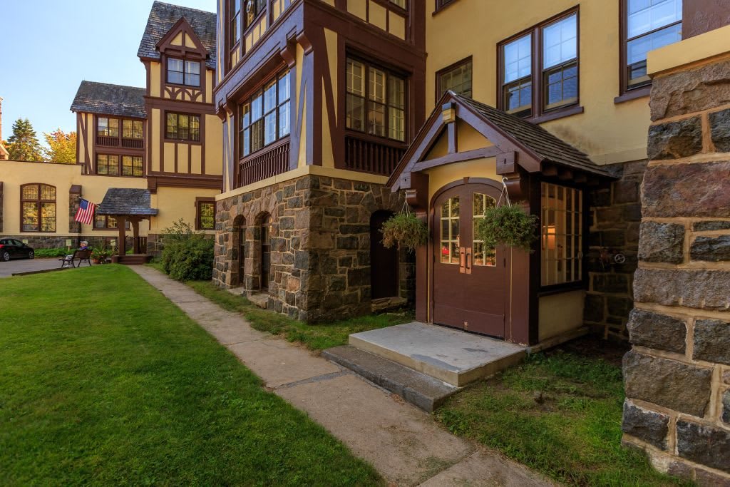 A charming Tudor-style building with a stone facade and wooden accents, surrounded by green landscaping.