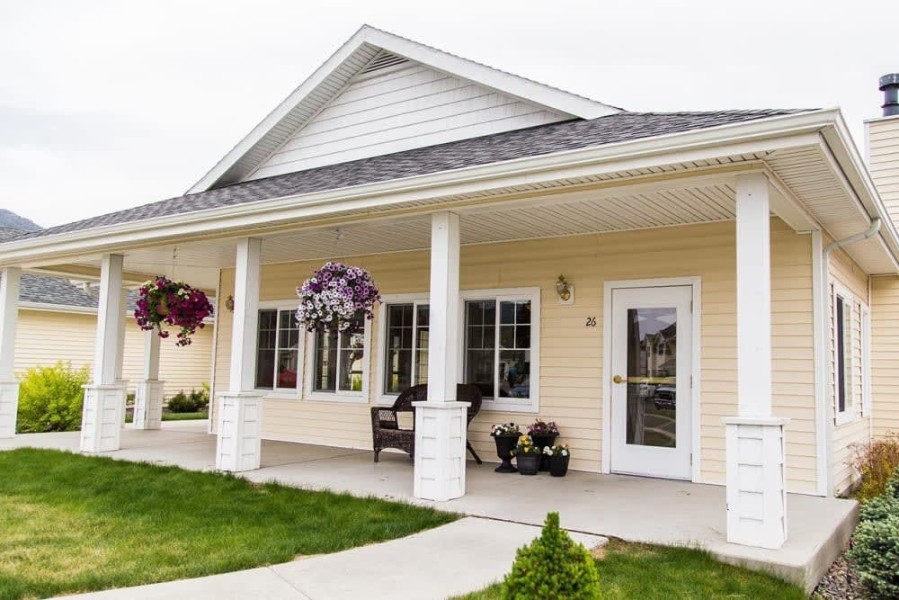 A charming house with a front porch and hanging plants.
