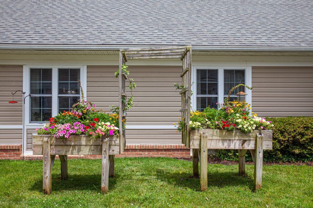 A charming garden setup with flower-filled planters and a decorative trellis in front of a house.
