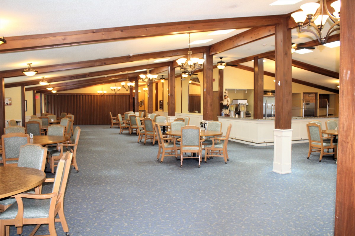 A spacious dining area with wooden beams and neatly arranged tables and chairs.