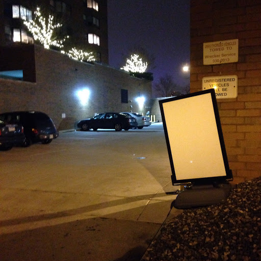 A quiet night scene in a parking lot, featuring an empty sign and dimly lit surroundings.