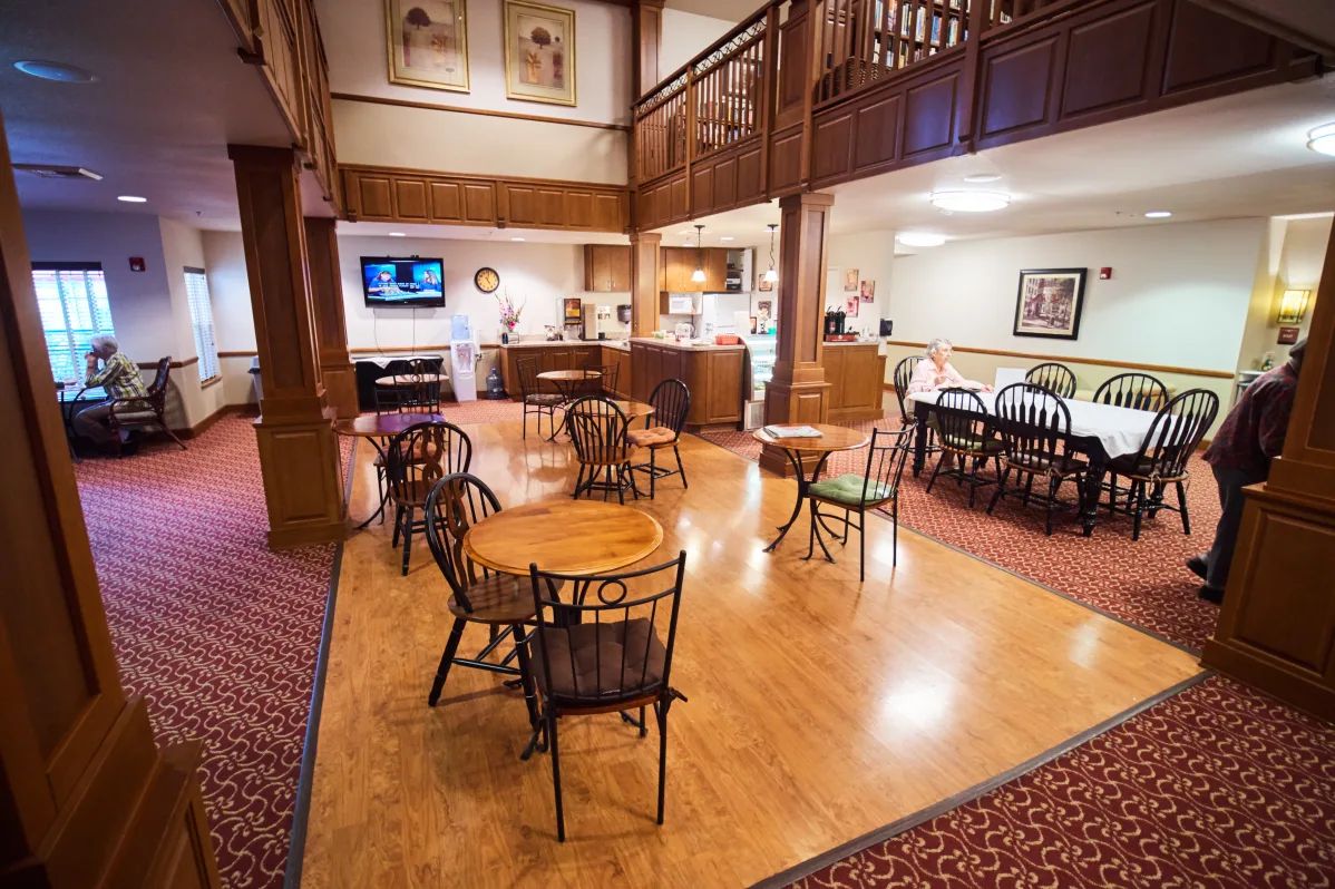 A cozy cafe interior with wooden floors, tables, and chairs.