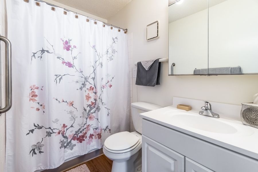 A clean and bright bathroom with a floral shower curtain.