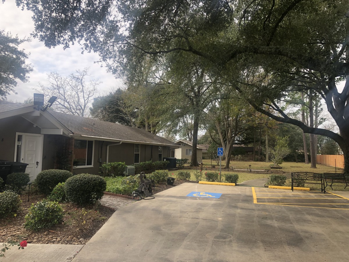 A small building surrounded by trees with an adjacent parking lot.