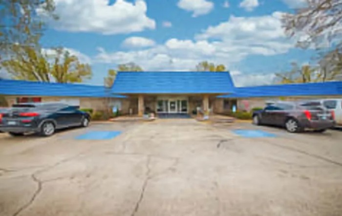 A small motel with a distinctive blue roof and parking area.