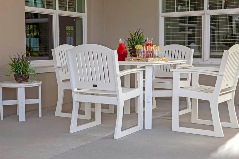 A cozy patio setup with white outdoor furniture, including several chairs and a table.