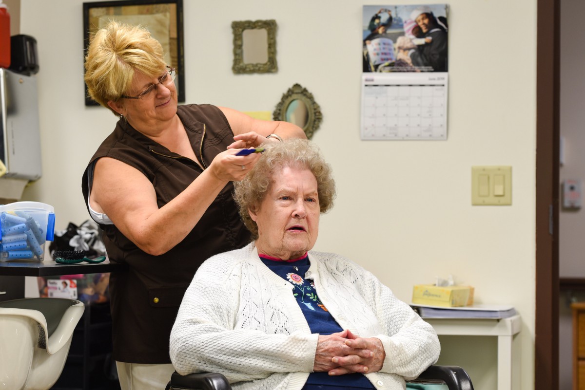 A hairdresser styles the hair of an elderly woman in a beauty salon.
