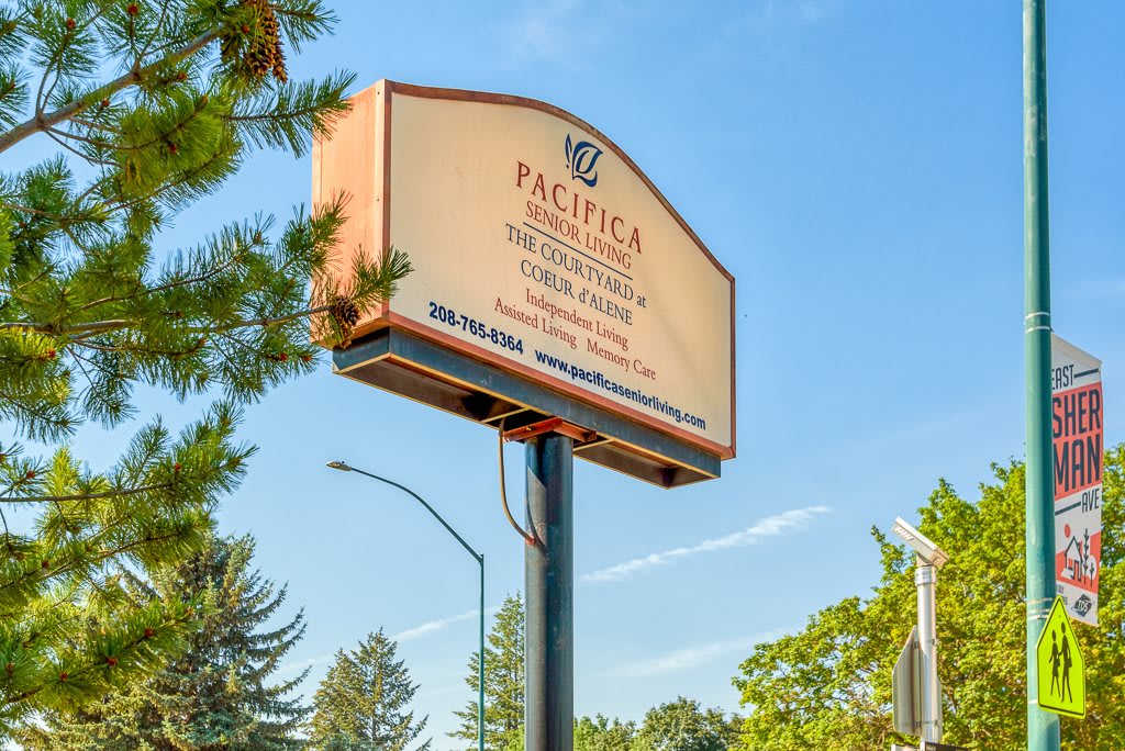 A sign for Pacifica Graduate Institute surrounded by trees under a clear blue sky.