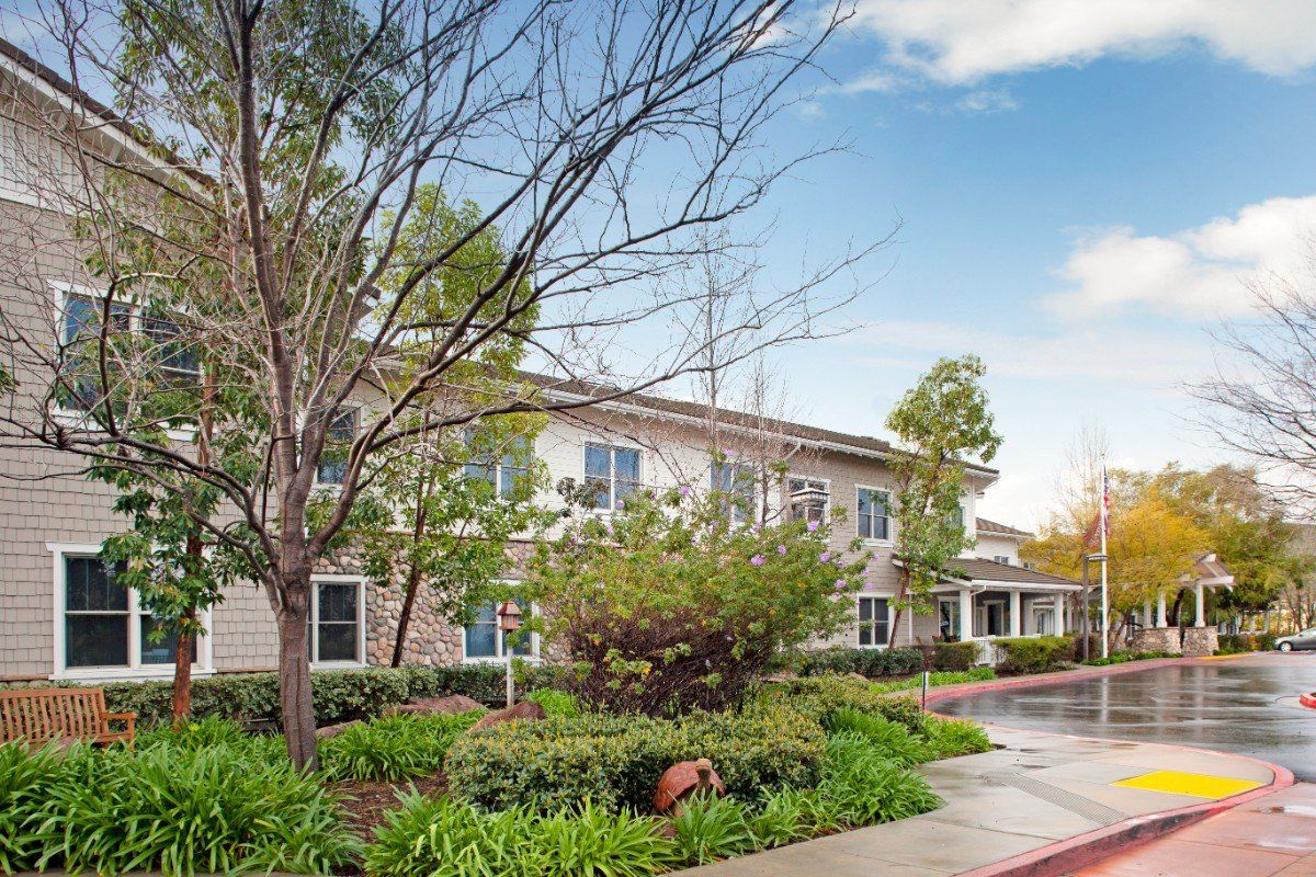 A well-landscaped residential building surrounded by trees with a clear sky in the background.