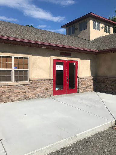 A view of a building's entrance showcasing red double doors and a stone facade.