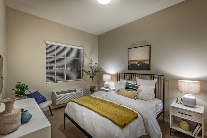 A modern bedroom interior with a neatly made bed, soft lighting, and wall art.