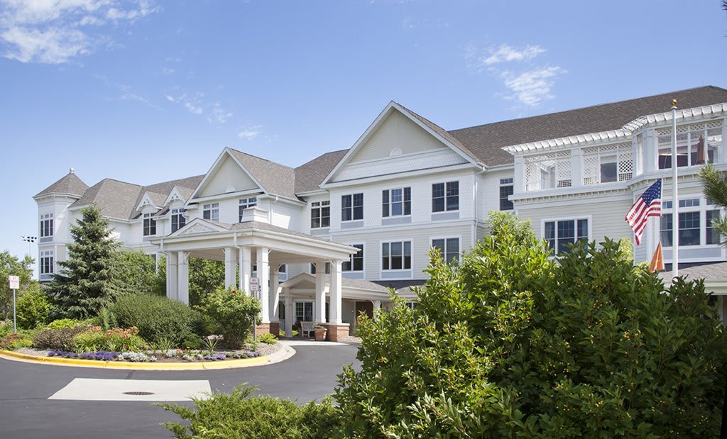 A large white building with a welcoming entrance surrounded by greenery.
