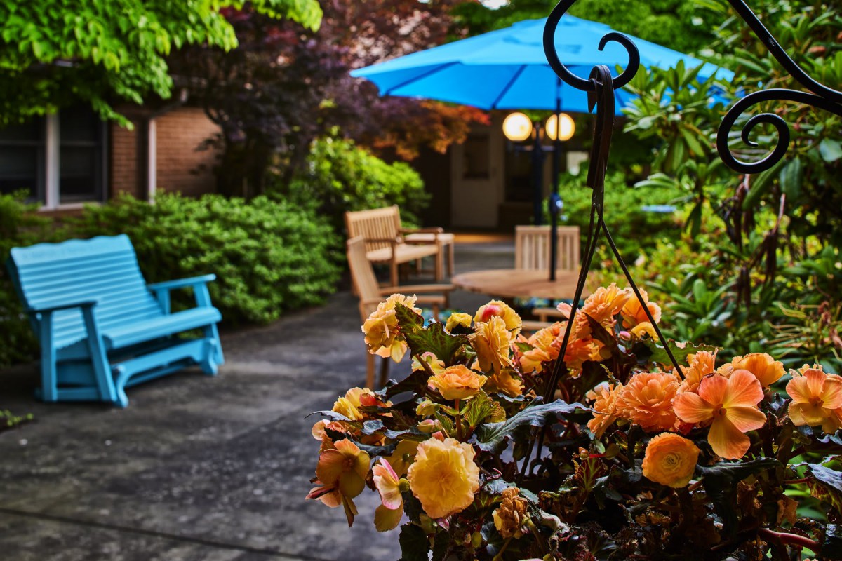 A cozy garden patio with vibrant flowers and outdoor seating.