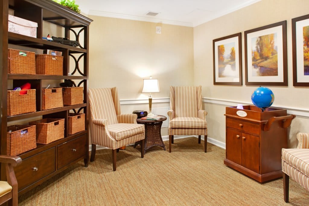 A cozy living room with two striped chairs, a small table, and a bookshelf.