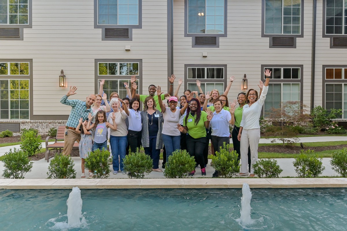 A group of people celebrating outdoors in front of a building with a fountain.