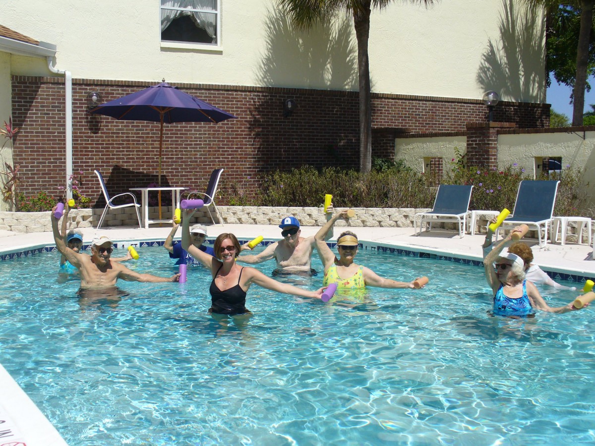 A group of people participating in a pool exercise class outdoors.