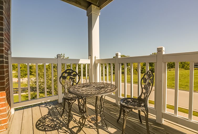 A sunny balcony with a wrought iron table and chairs set.