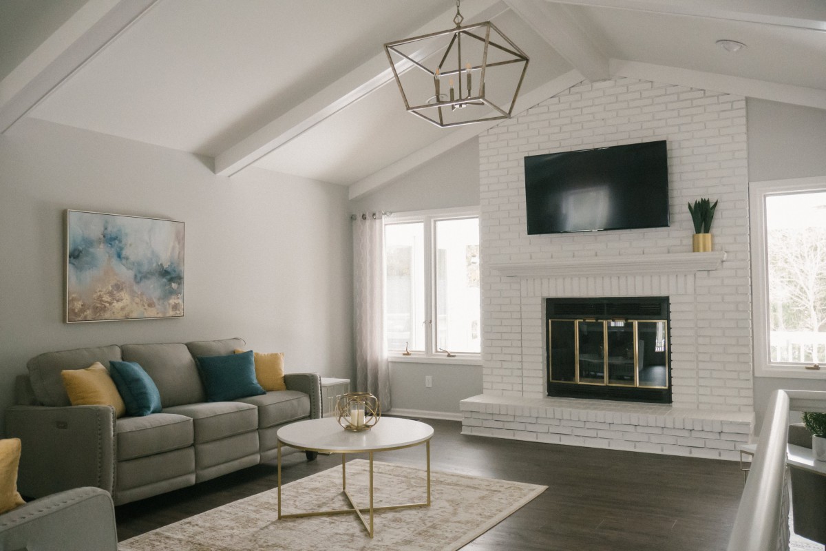 Modern living room with a vaulted ceiling, featuring a stylish chandelier and cozy fireplace.