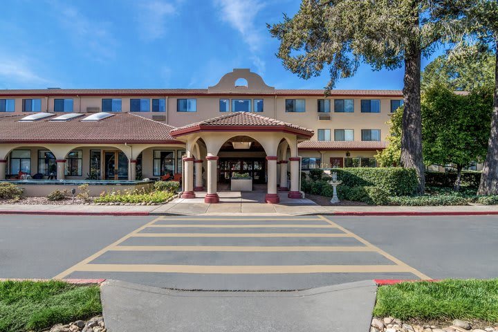 A hotel entrance with landscaped surroundings and clear blue sky.
