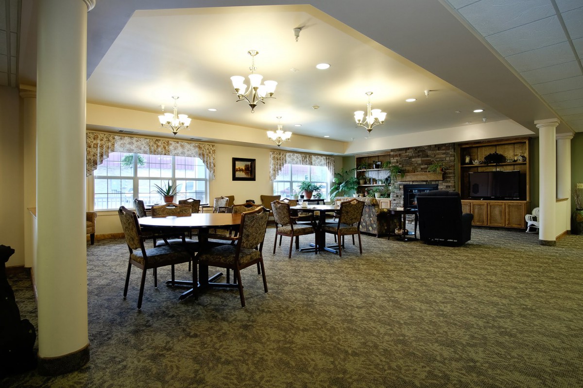 A spacious dining room with elegant chandeliers, multiple tables, and a cozy atmosphere.