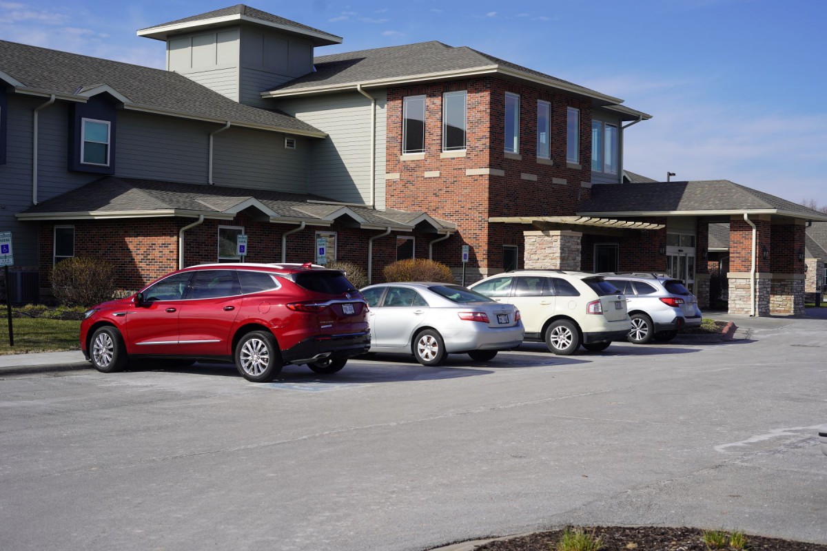 A suburban building with multiple cars parked in the parking lot.