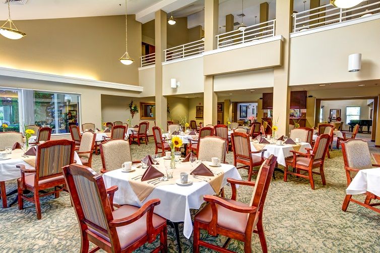 A spacious dining area with neatly arranged tables and chairs, featuring elegant decorations.