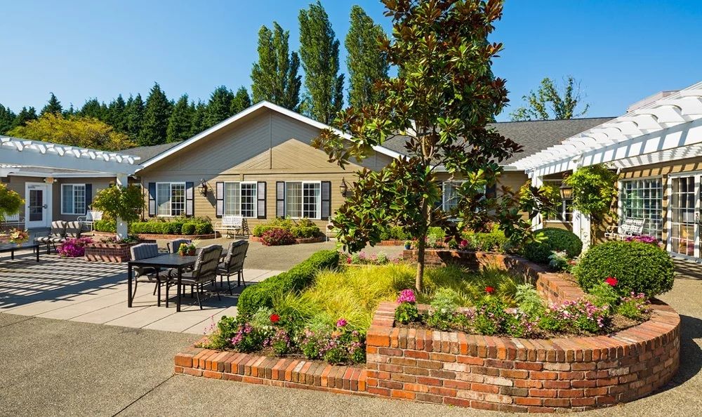 A charming house with well-maintained landscaping, featuring a garden, brick planter, and outdoor seating area.