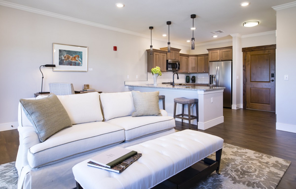 Modern open-concept living room and kitchen with cozy furnishings and warm lighting.