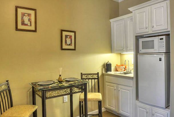 Cozy kitchenette with a small dining table and chairs next to white cabinets.