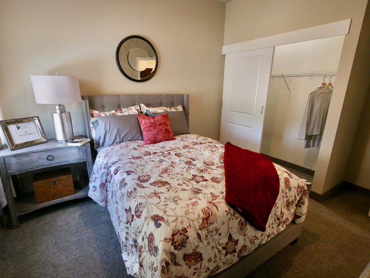 A cozy bedroom with floral bedding, a mirror, and an open closet.
