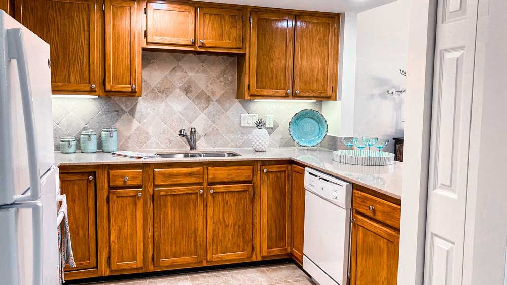 A kitchen interior featuring wooden cabinets, a tile backsplash, and decorative plates.